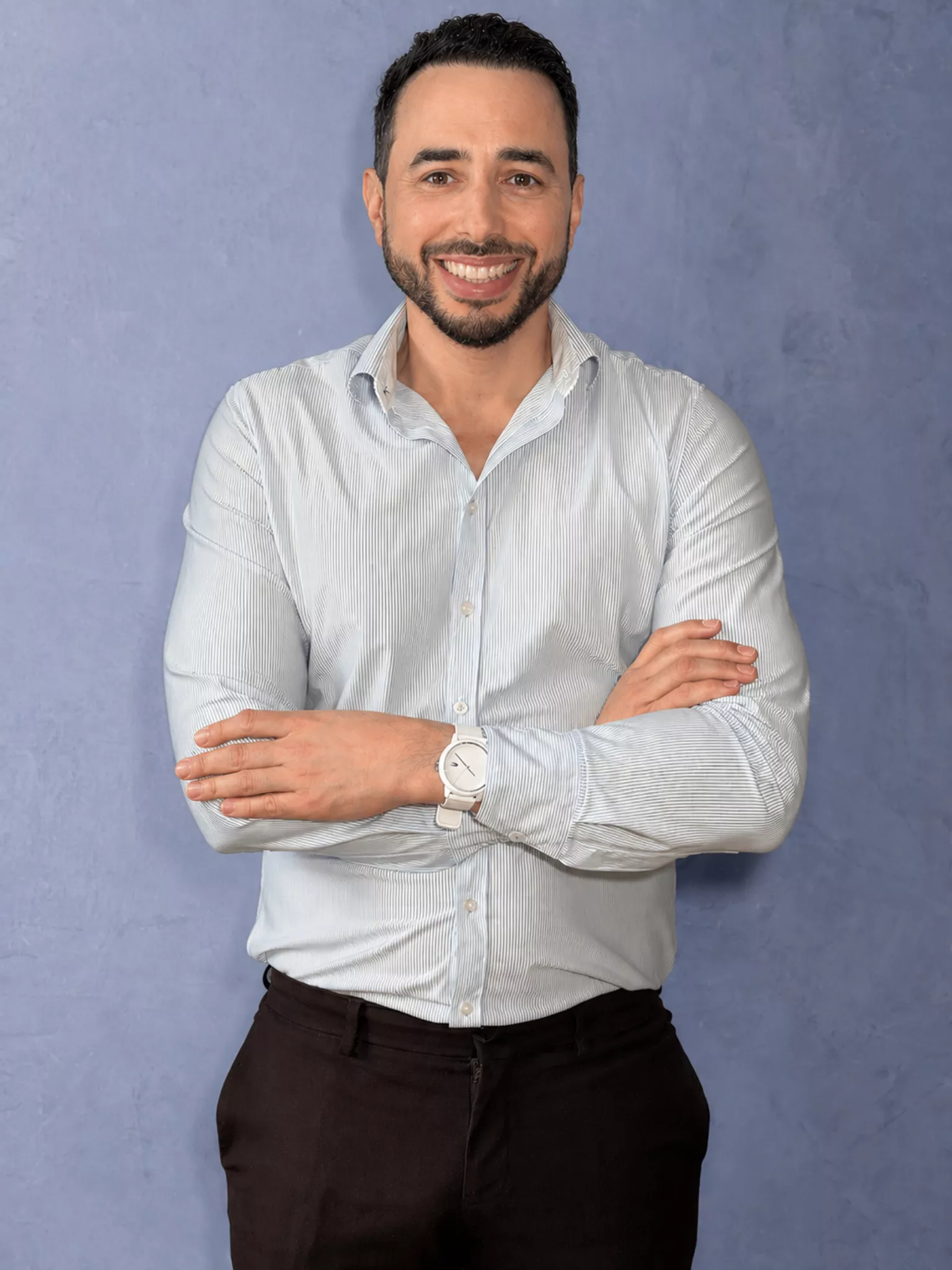 Homme souriant bras croisés sur fond bleu