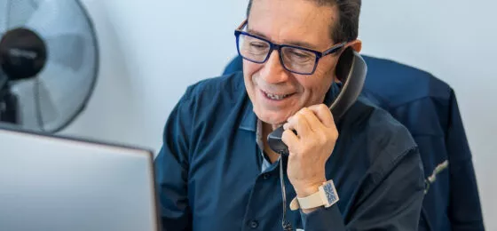 Homme souriant au téléphone devant ordinateur portable