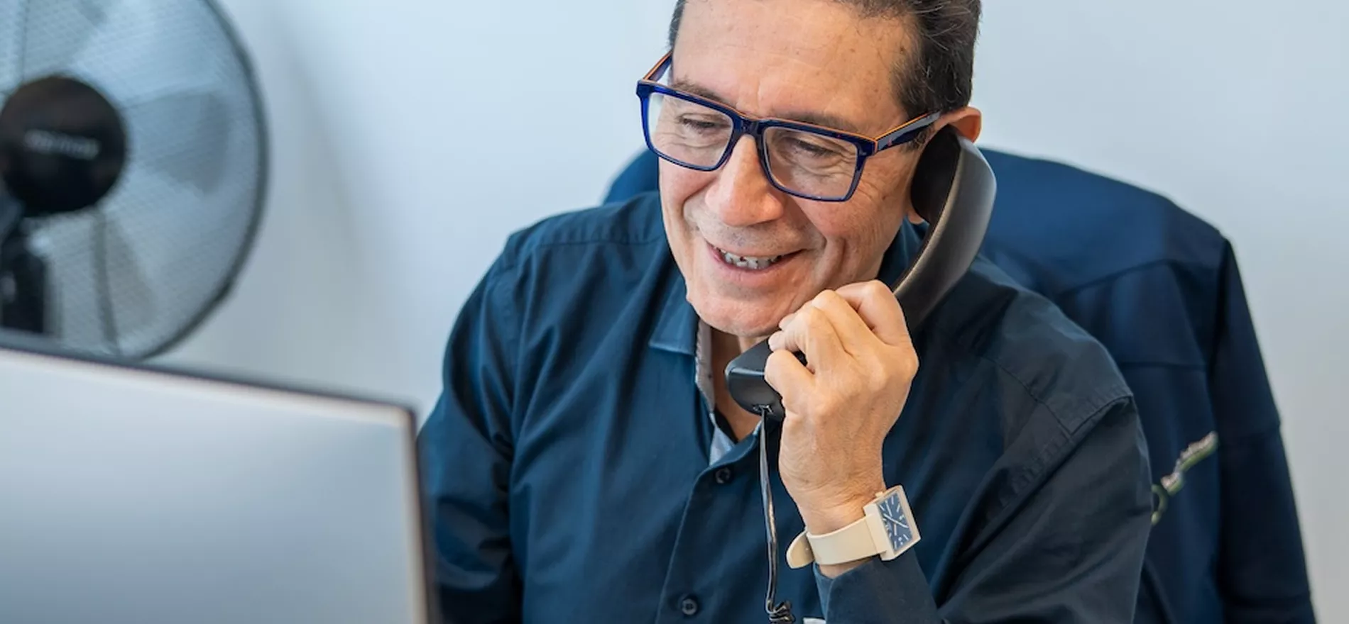 Homme souriant au téléphone devant ordinateur portable